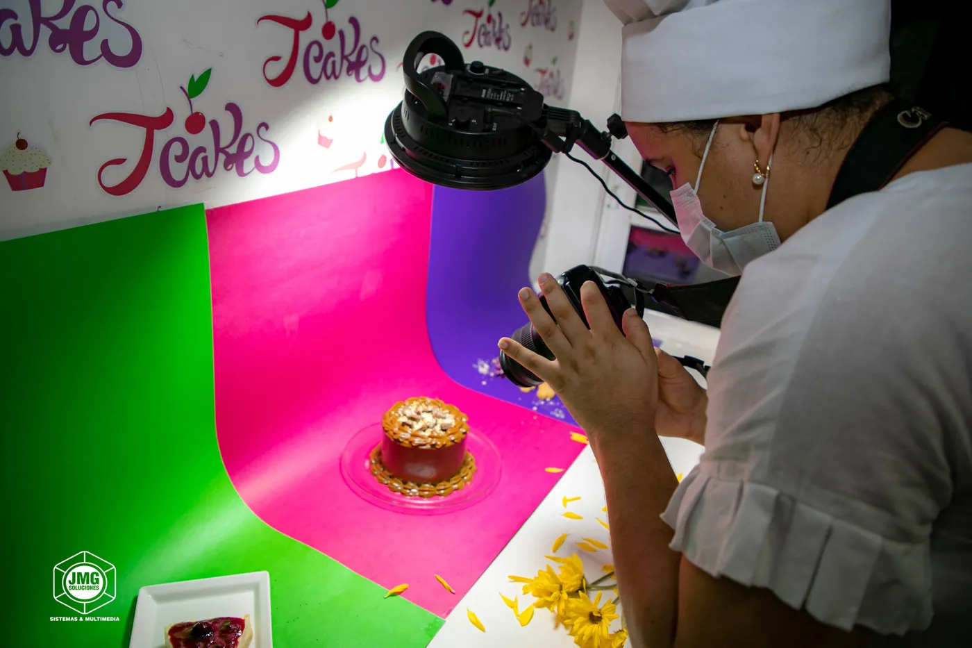 Fotógrafa graba con un estabilizador una torta sobre un fondo de colores en un set de repostería.