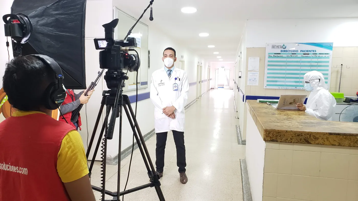 Equipo de JMG con cámara, micrófono de caña y luz entrevista a un médico en el pasillo de un hospital.