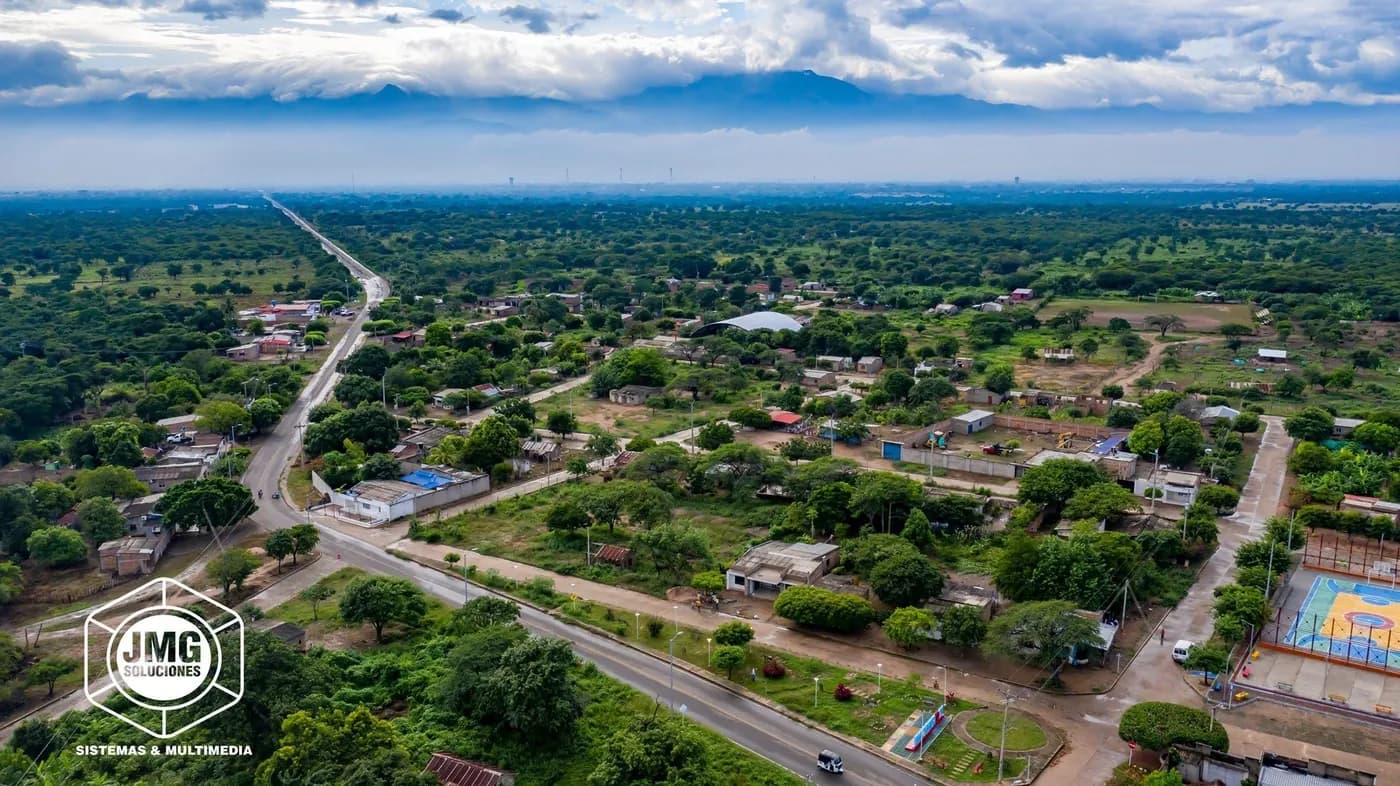 Vista aérea con dron de una vía principal que atraviesa un casco urbano arborizado.