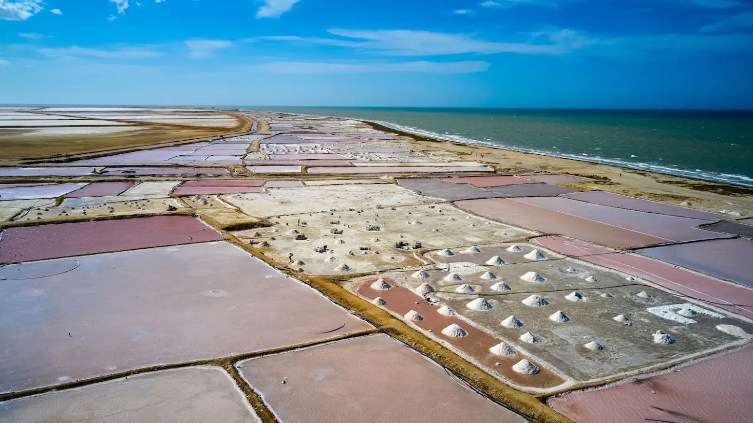 Vista aérea de las salinas de Manaure: piscinas rosadas y montículos de sal frente al mar Caribe.