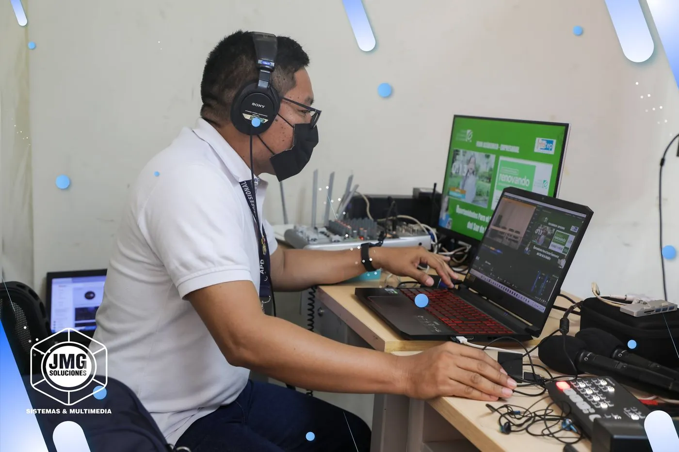 Operador de JMG con auriculares dirige una transmisión en vivo ante un portátil de edición, un mezclador de audio y un monitor de emisión.