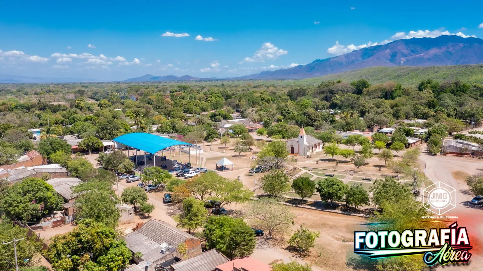 Vista aérea de la plaza de un pueblo de La Guajira con su iglesia y la sierra al fondo.