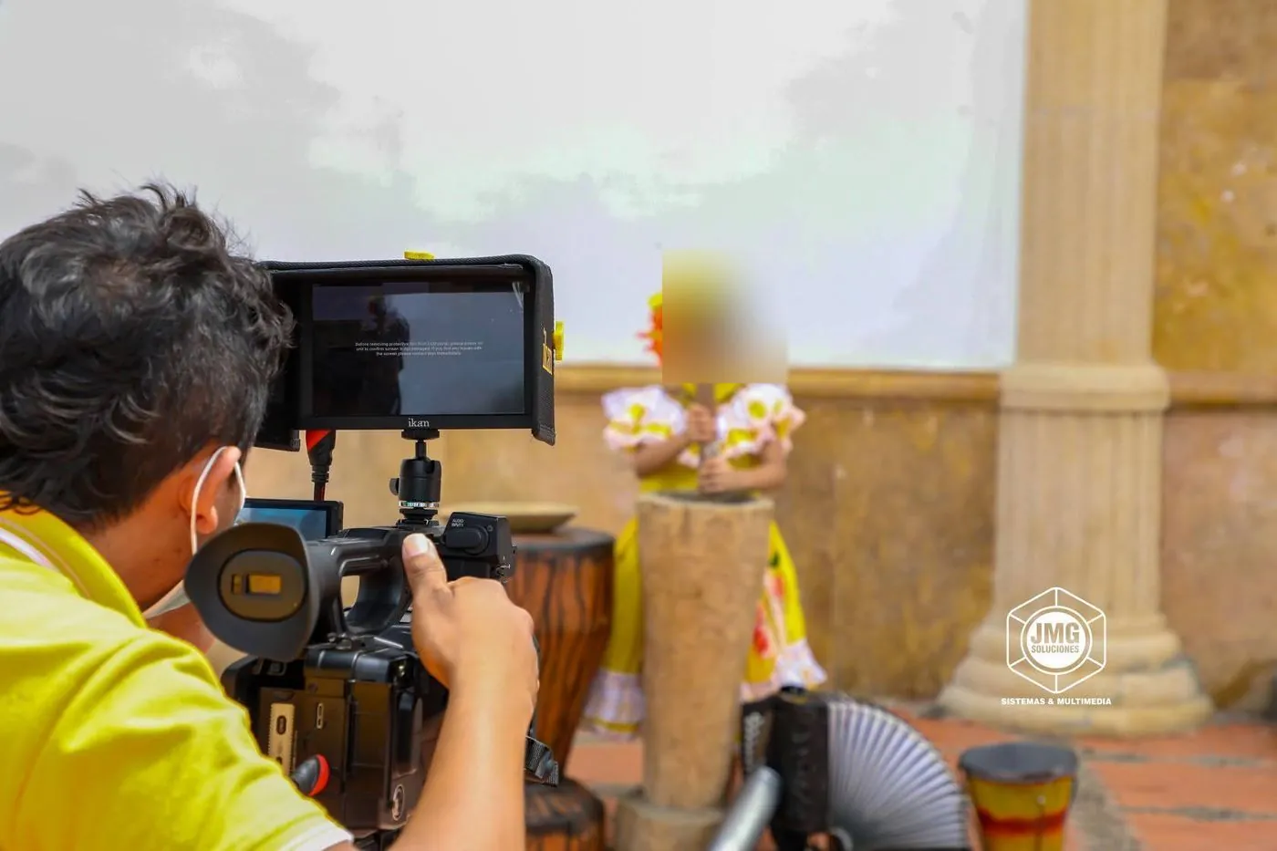 Operador de JMG graba con cámara y monitor de campo una escena de música y baile tradicional.