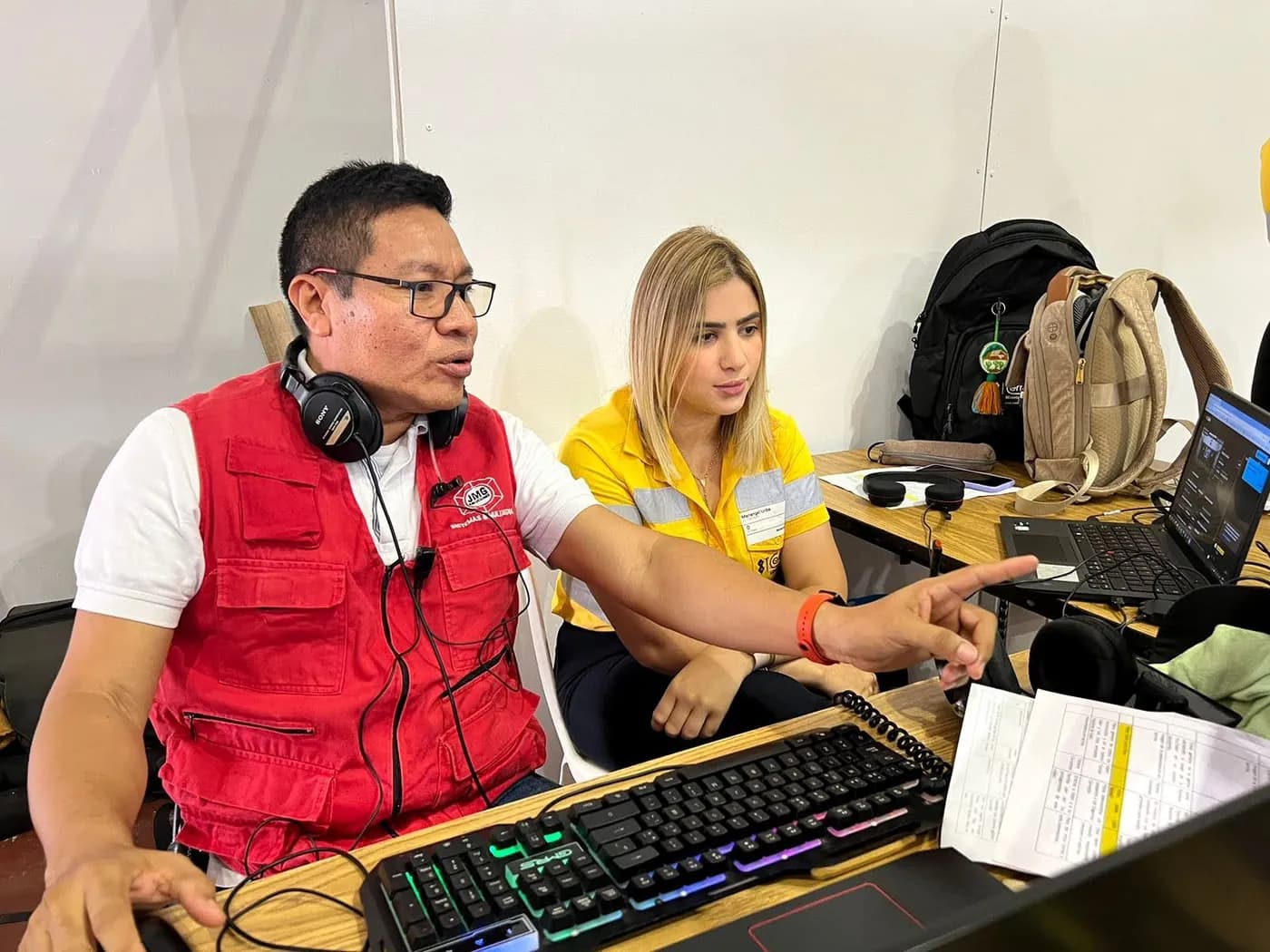 Director técnico de JMG con audífonos señala la pantalla del control junto a una integrante del equipo de Cerrejón con uniforme amarillo.