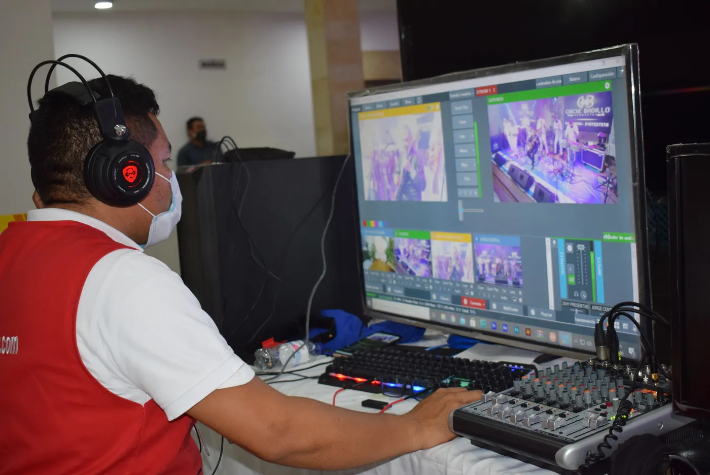 Operador de JMG con audífonos y tapabocas mezcla la señal en vivo frente a un monitor con varias cámaras.