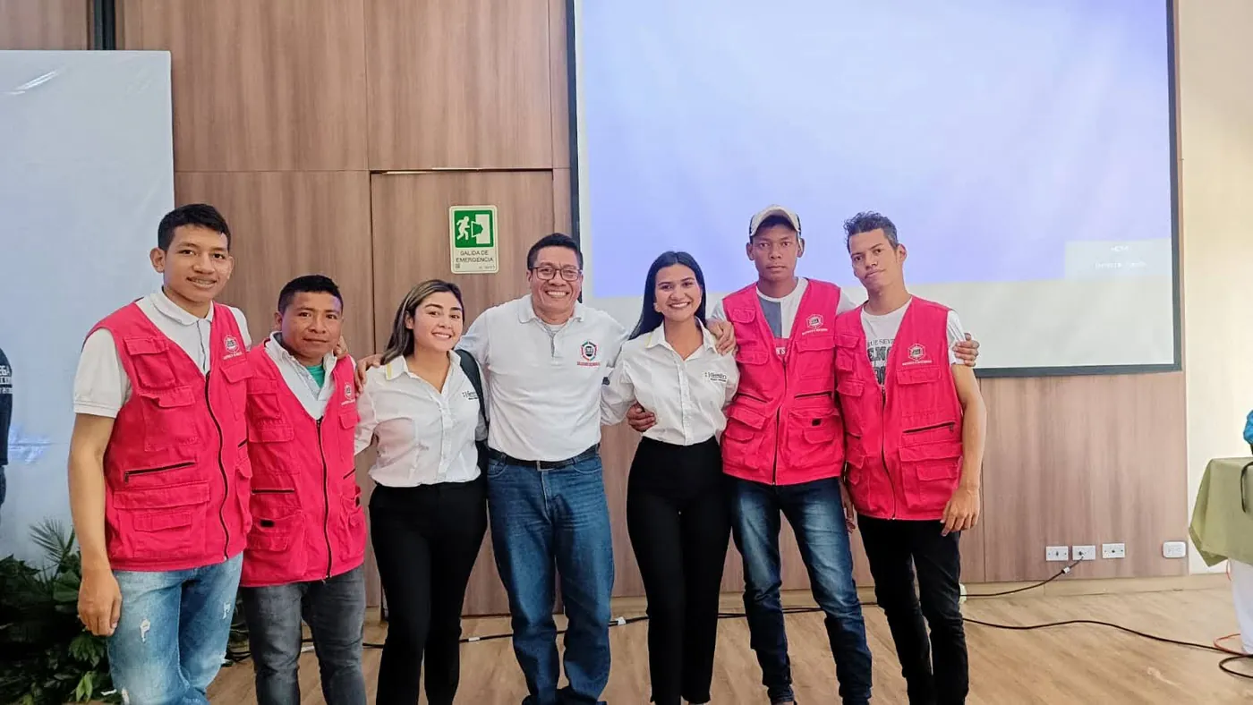 Equipo de JMG con chalecos rojos y organizadores de un acto institucional posan en el auditorio donde se hizo la transmisión.