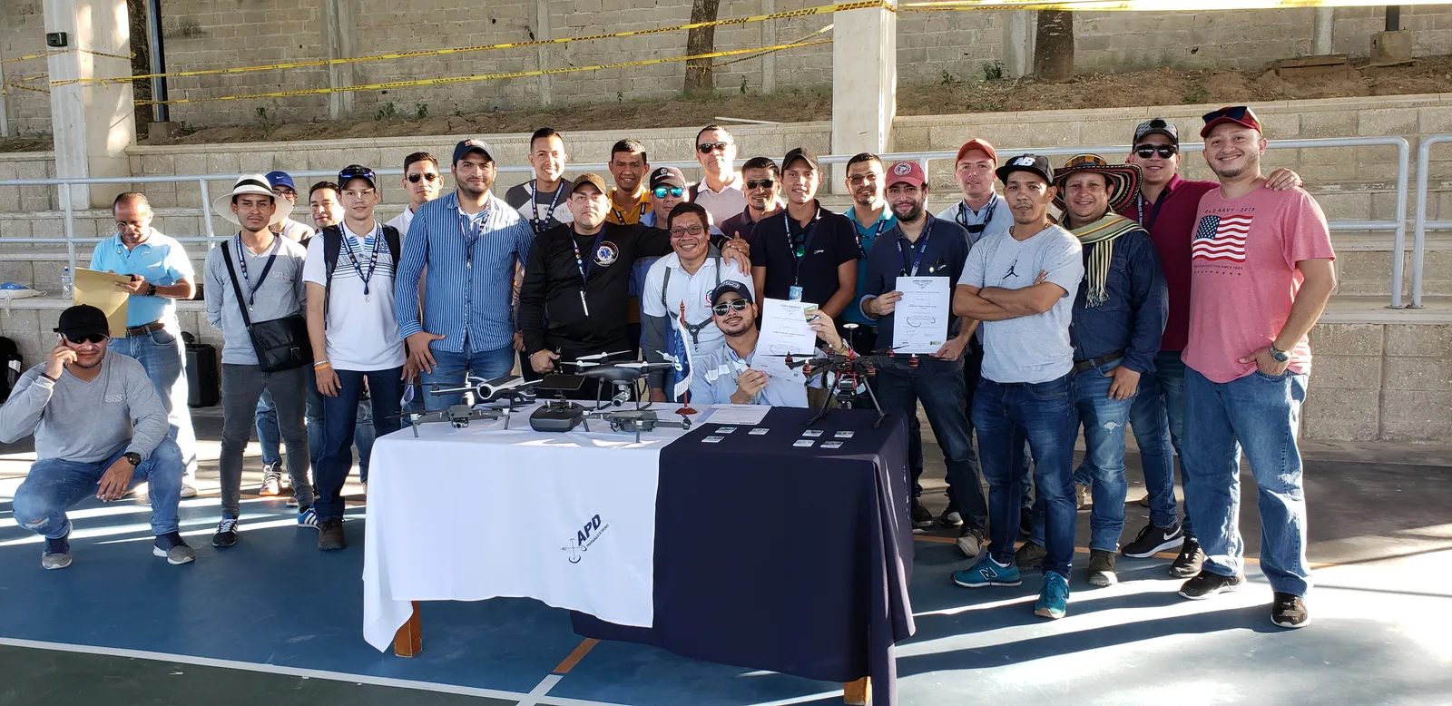Participantes de la APD reunidos detrás de una mesa con drones y certificados.